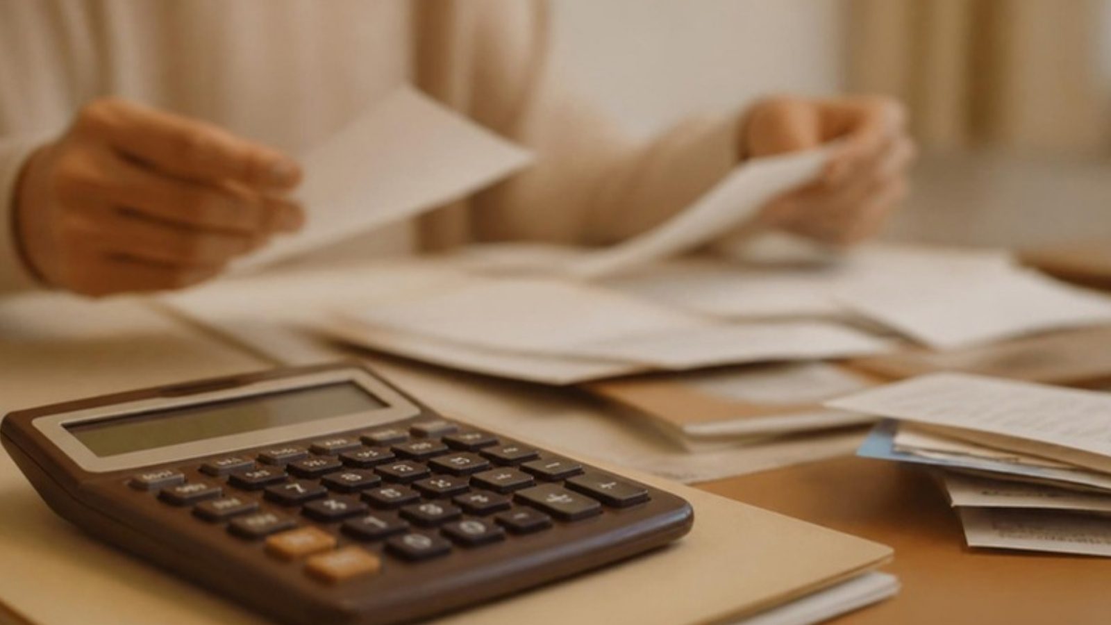 Mãos organizando comprovantes e calculadora para o cálculo do imposto na DSDP