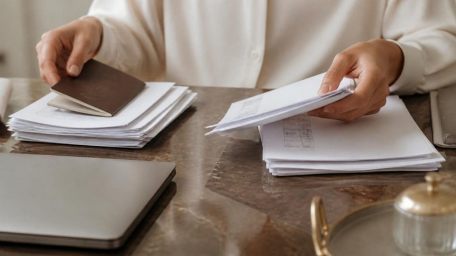Mãos organizando passaporte, contratos e contas usados como prova de residência fiscal